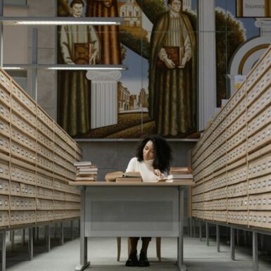 Librarian consults books in a library card aisle.