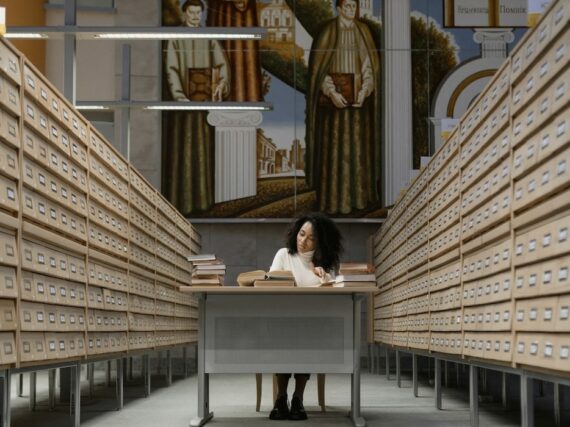 Librarian consults books in a library card aisle.